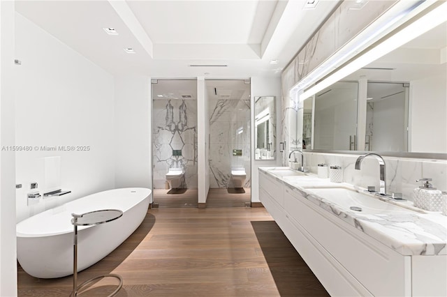 full bathroom with vanity, wood-type flooring, plus walk in shower, a raised ceiling, and toilet