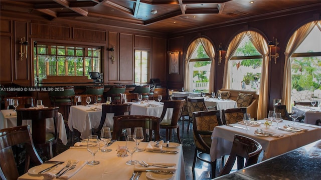 dining space featuring beamed ceiling, crown molding, coffered ceiling, and wooden walls