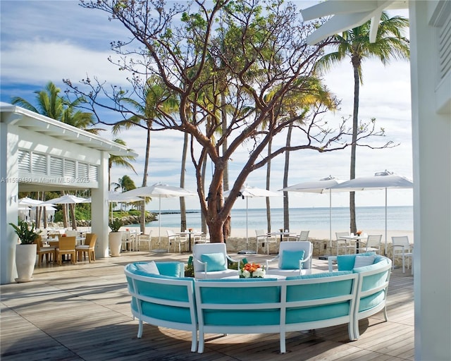 wooden deck with outdoor dining space, a water view, and an outdoor living space