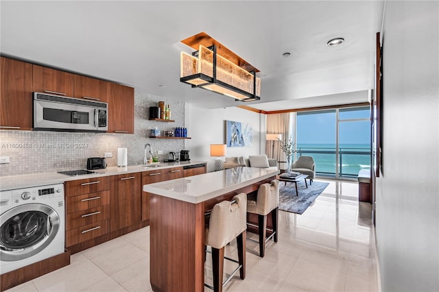 kitchen with a center island, a water view, tasteful backsplash, a kitchen bar, and washer / clothes dryer