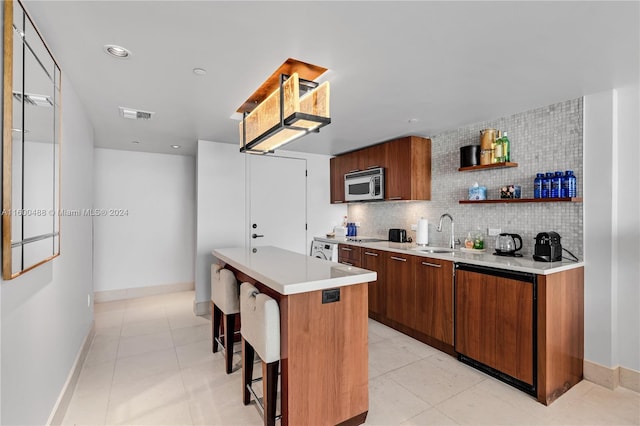 kitchen with a center island, backsplash, paneled dishwasher, light tile patterned floors, and a breakfast bar area