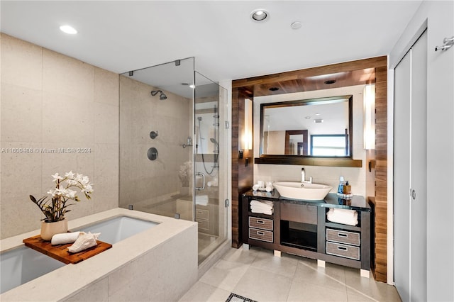 bathroom with plus walk in shower, vanity, tile patterned flooring, and tile walls