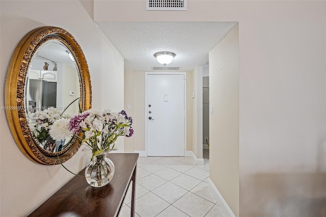 hall with a textured ceiling and light tile floors