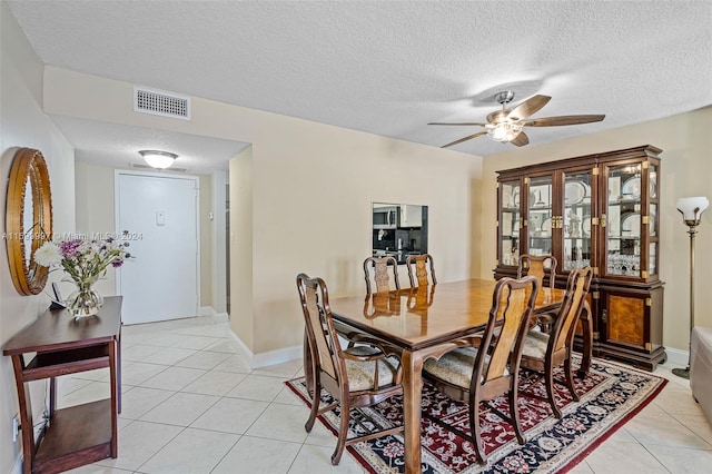 tiled dining room featuring ceiling fan and a textured ceiling