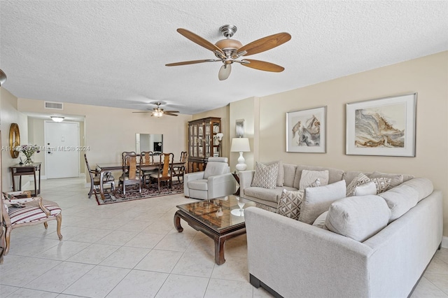 living room with a textured ceiling, light tile flooring, and ceiling fan