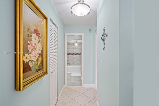 hall with a textured ceiling and light tile flooring