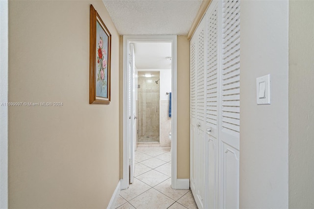 hall with a textured ceiling and light tile floors