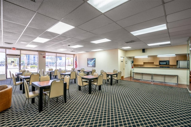 carpeted dining area featuring a drop ceiling