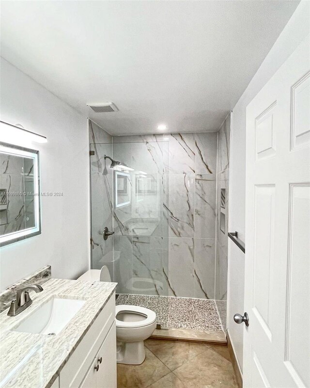 bathroom featuring tile floors, vanity with extensive cabinet space, and toilet