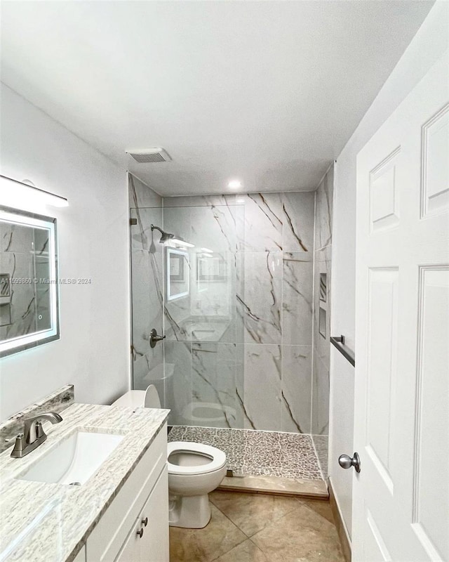 bathroom with vanity, tiled shower, and toilet