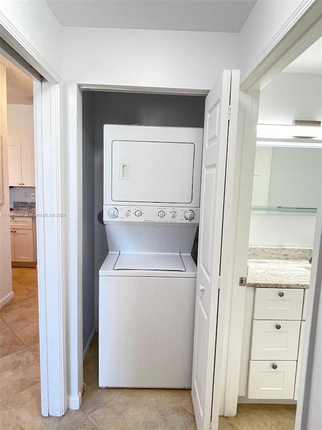 laundry area with stacked washer / dryer and light tile floors