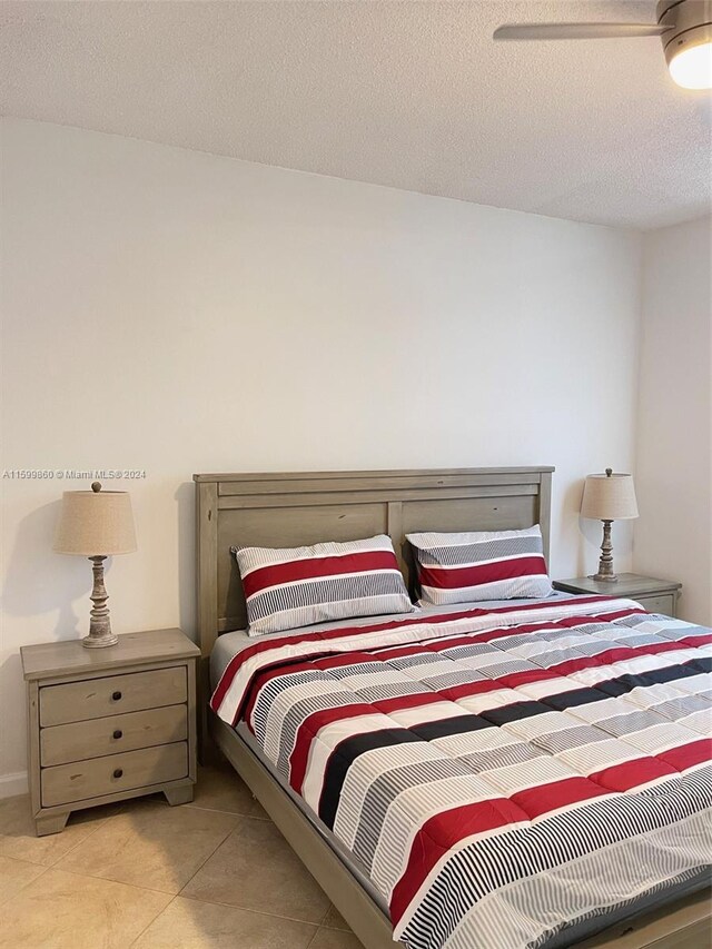 bedroom with a textured ceiling and light tile floors