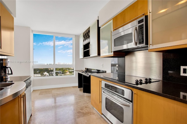 kitchen featuring appliances with stainless steel finishes, dark stone counters, and backsplash