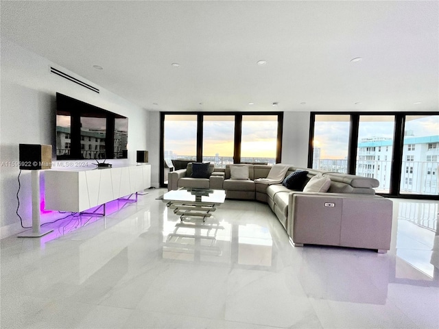 living room featuring plenty of natural light, light tile patterned flooring, and a wall of windows