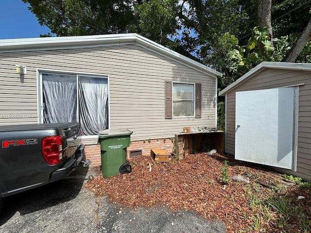 view of property exterior with crawl space, a storage unit, and an outbuilding