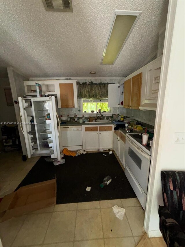 kitchen featuring white appliances, a textured ceiling, tasteful backsplash, and light tile floors