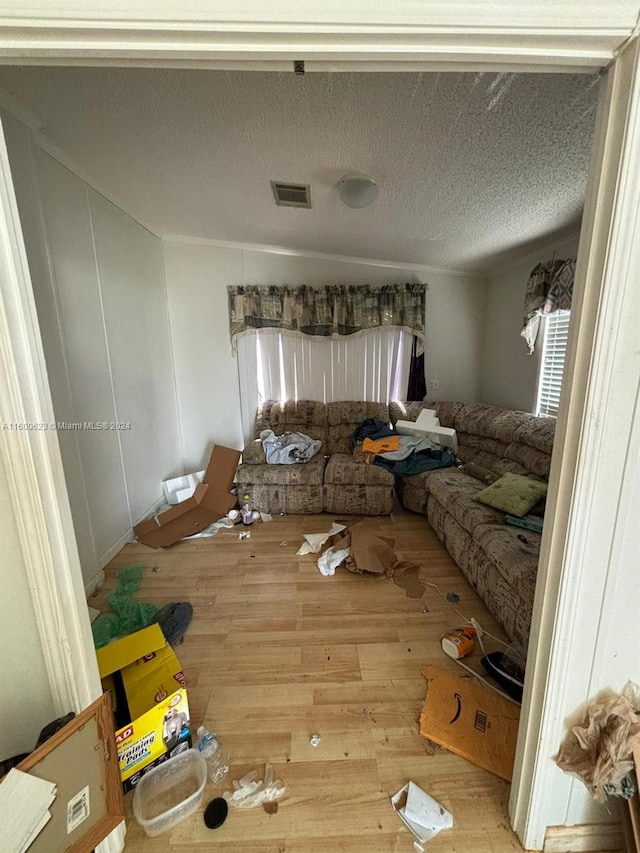 unfurnished living room with wood finished floors, visible vents, and a textured ceiling