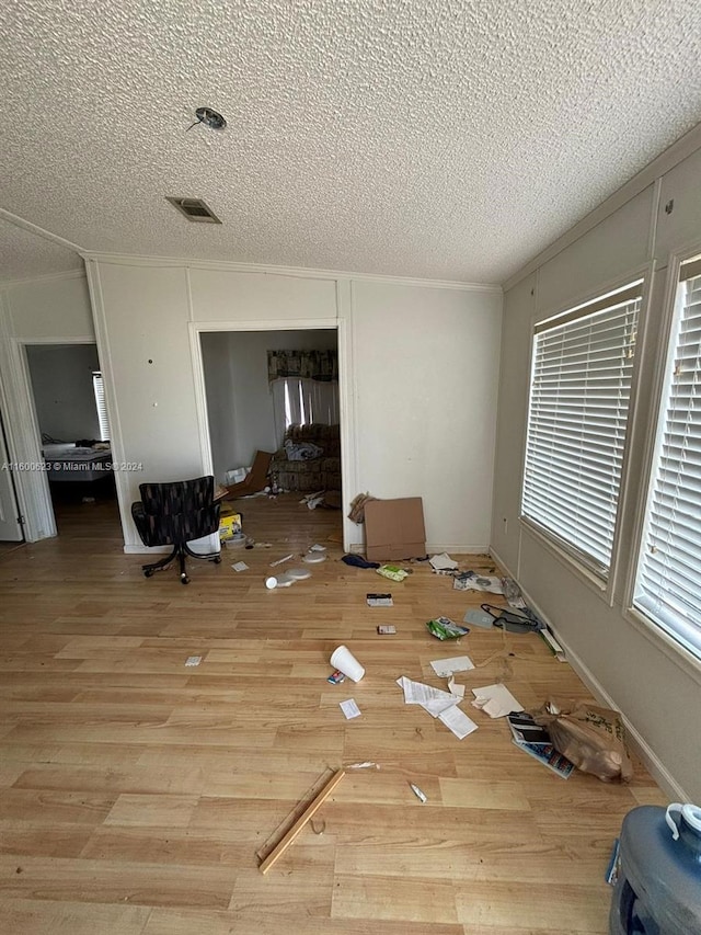 interior space with ornamental molding, wood finished floors, visible vents, and a textured ceiling