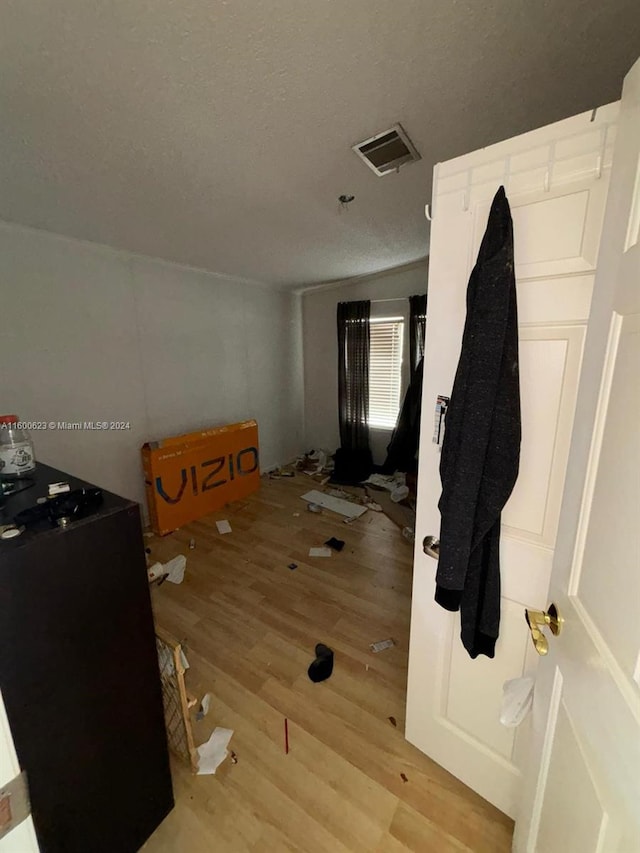 bedroom with light wood finished floors, visible vents, and a textured ceiling