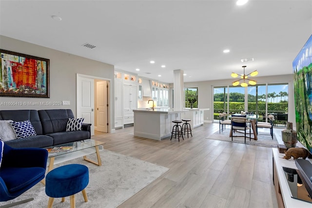 living room featuring a notable chandelier, light hardwood / wood-style flooring, and sink