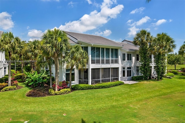 rear view of house featuring a yard and a sunroom