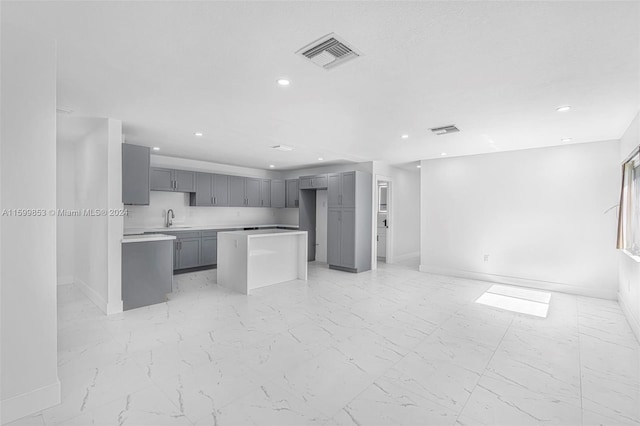 kitchen featuring a center island, gray cabinetry, and sink