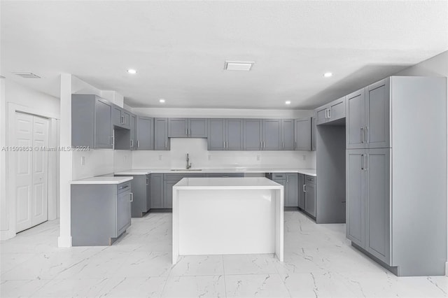 kitchen featuring gray cabinets, a kitchen island, and sink