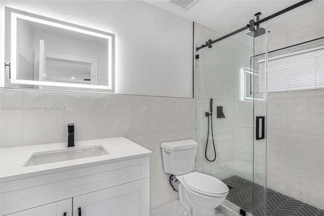 bathroom featuring vanity, toilet, a shower with door, and tile walls