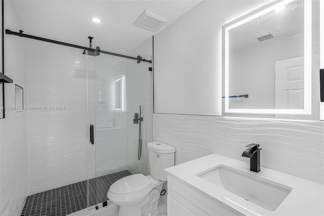 bathroom with vanity, toilet, a shower with shower door, and tile walls