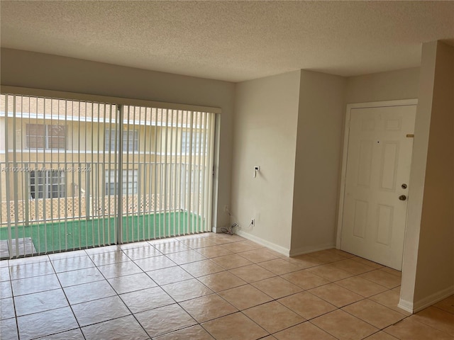 unfurnished room with a textured ceiling, light tile flooring, and a wealth of natural light