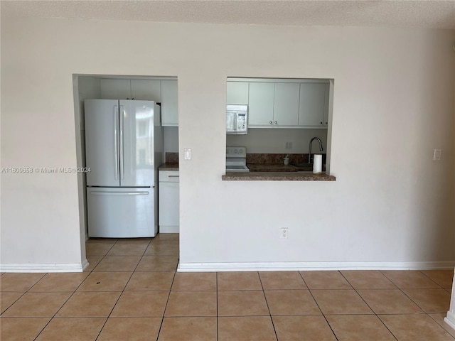 kitchen featuring tile flooring, white microwave, and fridge