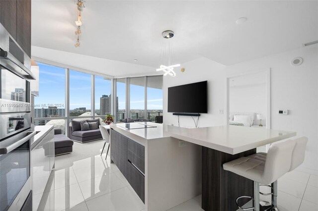 kitchen featuring light tile floors, an inviting chandelier, rail lighting, hanging light fixtures, and a breakfast bar