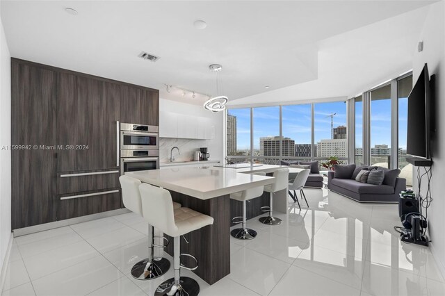 dining space with floor to ceiling windows, sink, track lighting, and light tile flooring