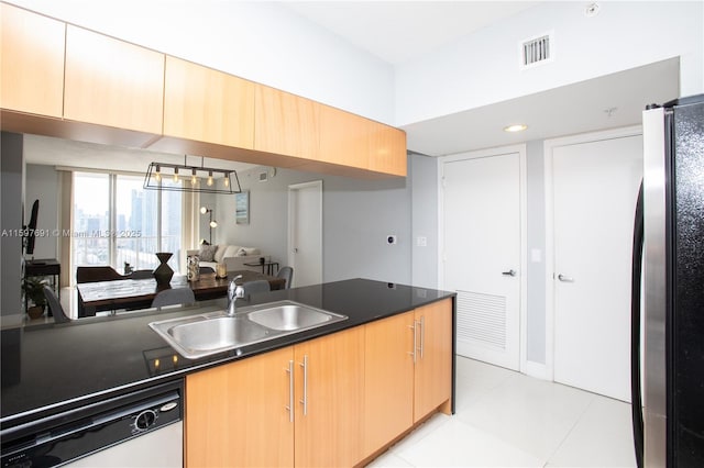 kitchen with dark countertops, dishwasher, light tile patterned floors, freestanding refrigerator, and a sink