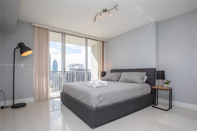 tiled bedroom with track lighting, baseboards, a wall of windows, a view of city, and access to outside