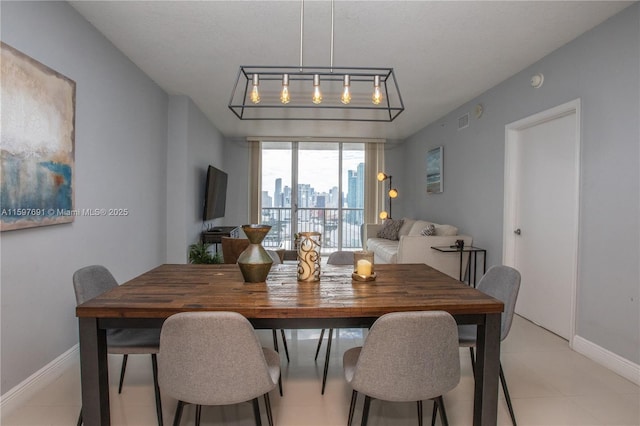 dining area with light tile patterned floors, visible vents, rail lighting, and baseboards