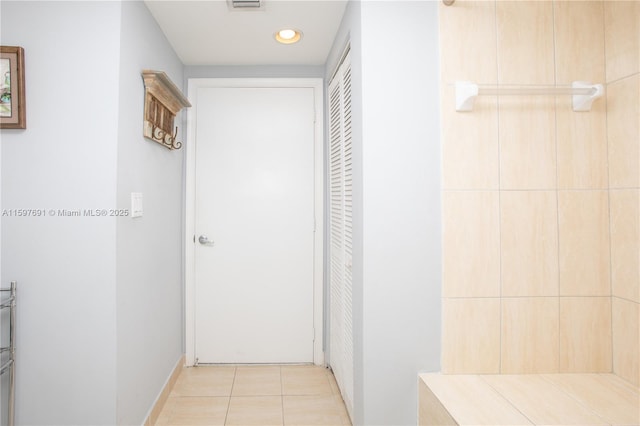 hallway featuring light tile patterned floors and visible vents