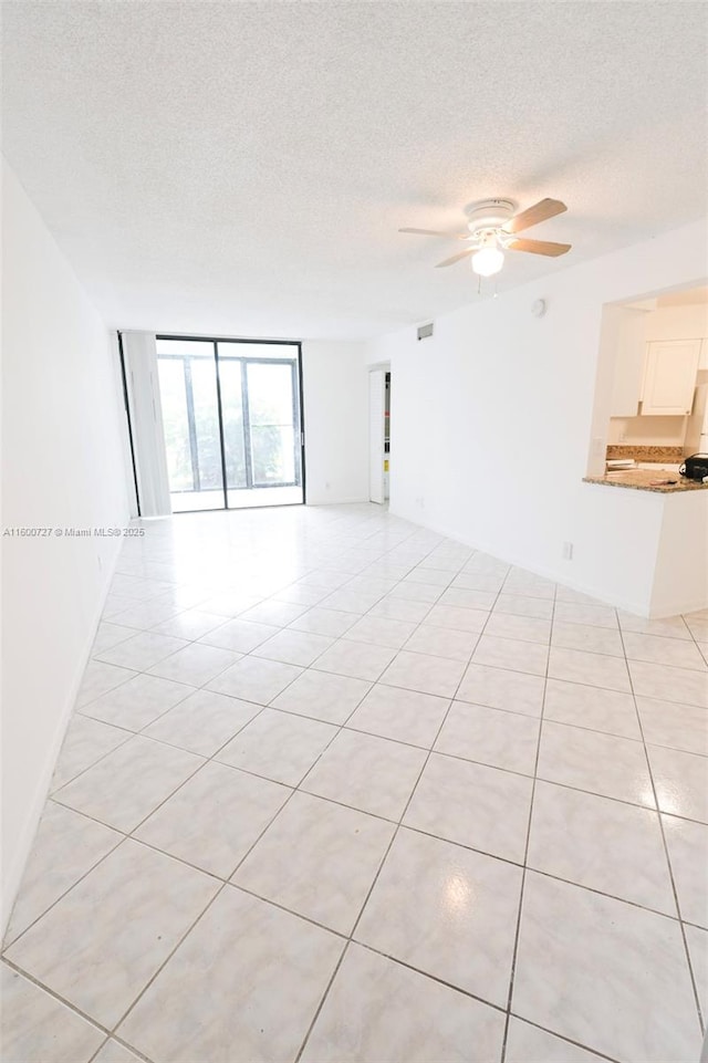 empty room with ceiling fan, light tile patterned floors, and floor to ceiling windows