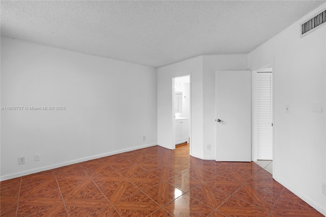 tiled empty room featuring a textured ceiling