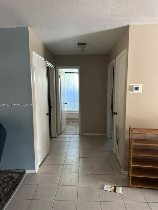 corridor with light tile patterned floors and a textured ceiling