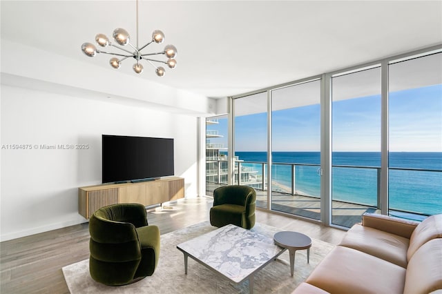 living room featuring a wall of windows, a notable chandelier, wood finished floors, and baseboards