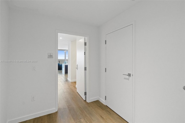 hall with baseboards and light wood-style floors