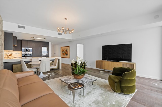 living room featuring light wood-type flooring, a notable chandelier, and sink