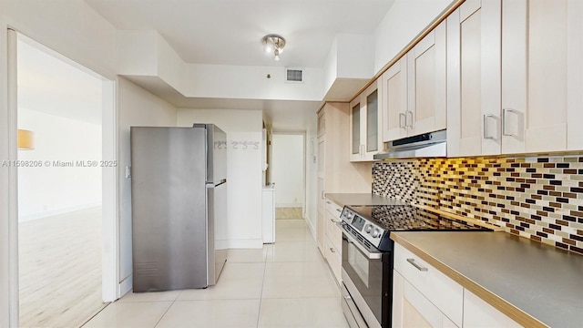 kitchen with backsplash, white cabinetry, light tile patterned floors, and appliances with stainless steel finishes