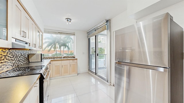 kitchen featuring decorative backsplash, light brown cabinetry, light tile patterned floors, and appliances with stainless steel finishes