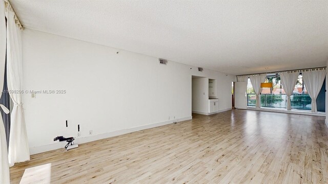 unfurnished room featuring light wood-type flooring and a textured ceiling