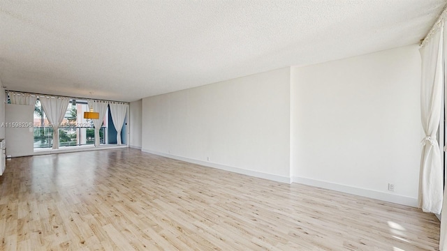 unfurnished room featuring light hardwood / wood-style floors and a textured ceiling