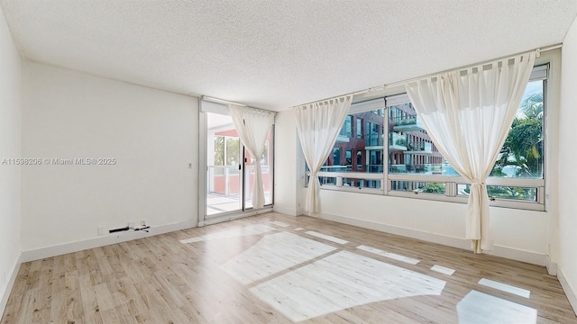 unfurnished room with a textured ceiling, light hardwood / wood-style flooring, and a healthy amount of sunlight