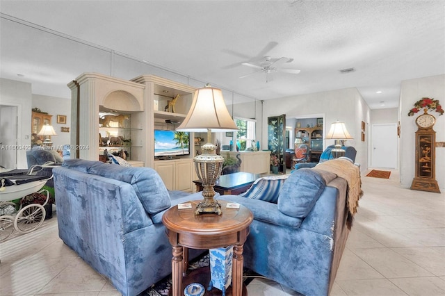 living room featuring ceiling fan, light tile patterned floors, and a textured ceiling