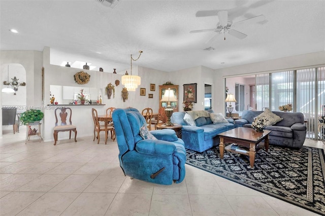 living room featuring ceiling fan with notable chandelier, light tile patterned flooring, and a textured ceiling